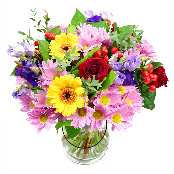 This image shows a lush mixed bouquet arranged with the practiced hand of a local florist, standing proudly in a clear glass vase against a crisp white background. The arrangement has a rounded, slightly domed shape, with each flower thoughtfully placed so that no single bloom overwhelms the others. At the centre, rich red roses open in layered spirals, their velvety petals hinting at classic romance and heartfelt emotion. Rising alongside them, a pair of bright yellow gerbera daisies with warm brown-orange centres radiate cheerful energy, bringing a joyful, sunlit quality that feels right at home in a Collier Row living room on a happy occasion. Around this core, generous sprays of soft pink daisies or chrysanthemums spill outward, their multiple slender petals and tiny golden centres lending a touch of casual charm and extra volume. Threaded delicately through the pink and yellow tones are elegant stems of lisianthus in deep purple and lavender hues; some blossoms are fully open, showing off their ruffled, bell-shaped petals, while others remain as slender buds, adding anticipation and depth. Small clusters of round, bright red hypericum berries nestle between petals and leaves, their glossy surfaces catching the light and giving the eye something playful to rest on. A rich mix of greenery - from large, substantial leaves to fine, airy sprigs - embraces the flowers and softens the edges of the bouquet, echoing the natural greenery you might see around Collier Row's residential streets and gardens. Inside the simple glass vase, the neatly trimmed stems fan out in clear water, underlining the freshness of the design. The overall mood is one of warm celebration and thoughtfulness, ideal for birthdays, anniversaries, or spontaneous surprise deliveries across Collier Row.